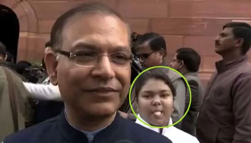 a girl behind Minister Jayant Sinha looks into the camera and sticks out her tongue multiple times Video Goes Viral