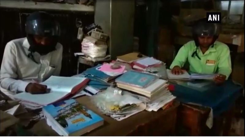 UP Banda Electricity dept employees wear helmets to protest themselves from crumbling building