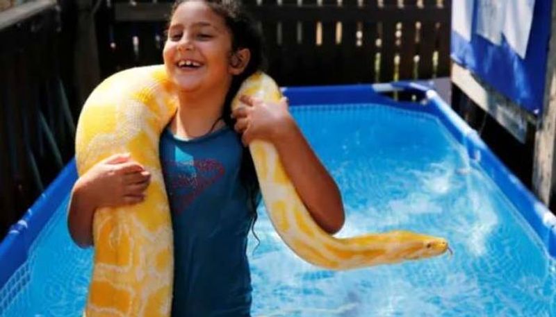 girl goes swimming in the pool with her pet python