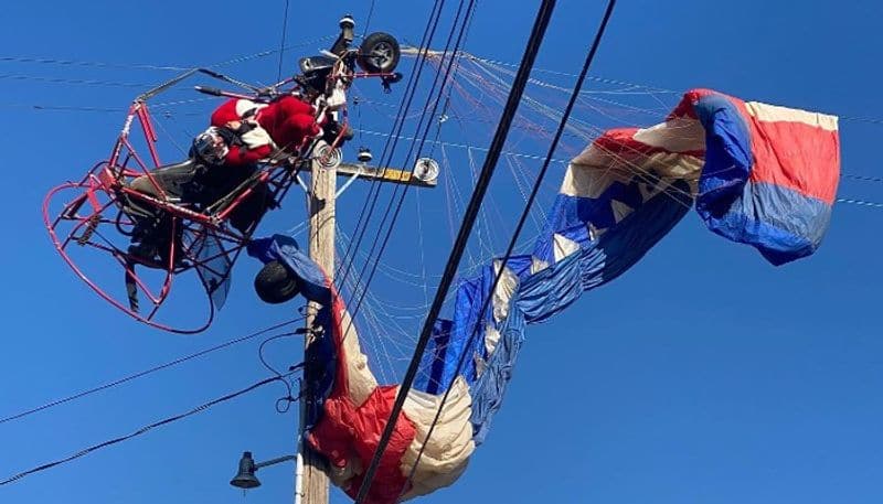 man in santa claus costume gets tangled in power lines after his parachute crashed