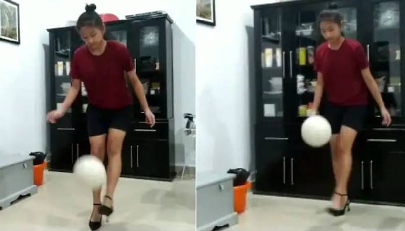 girl juggles ball with feet while wearing heels