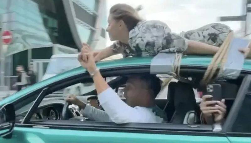 Man drives with girl friend who tied on the car roof