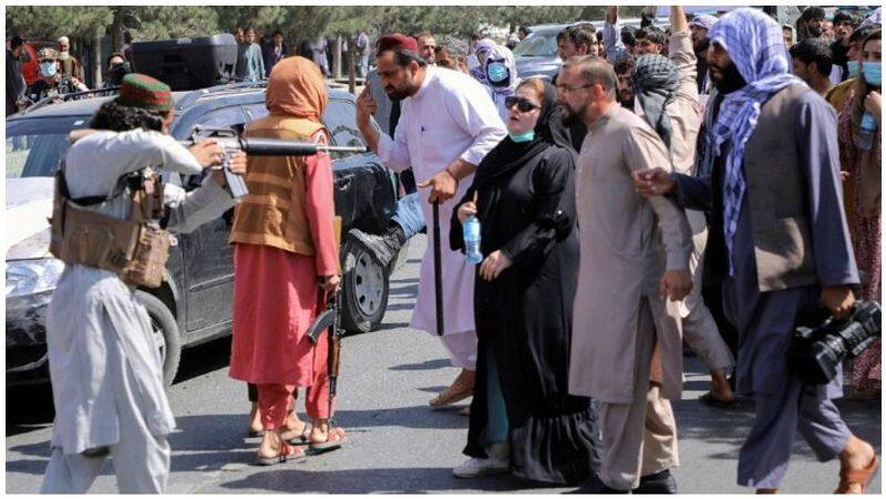 Afghan woman stands face to face against Taliban armed man image called iconic