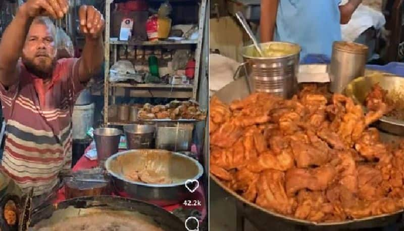 man dips his hand in hot oil to take fried chicken out