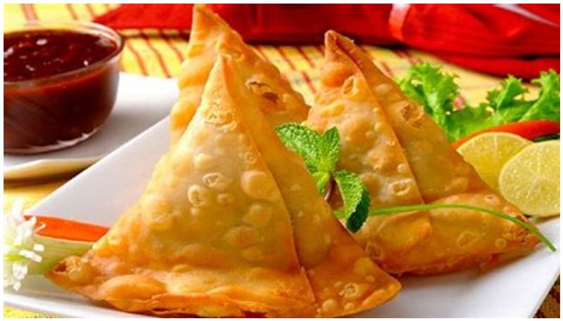 street food vendor prepares sandwich with samosa