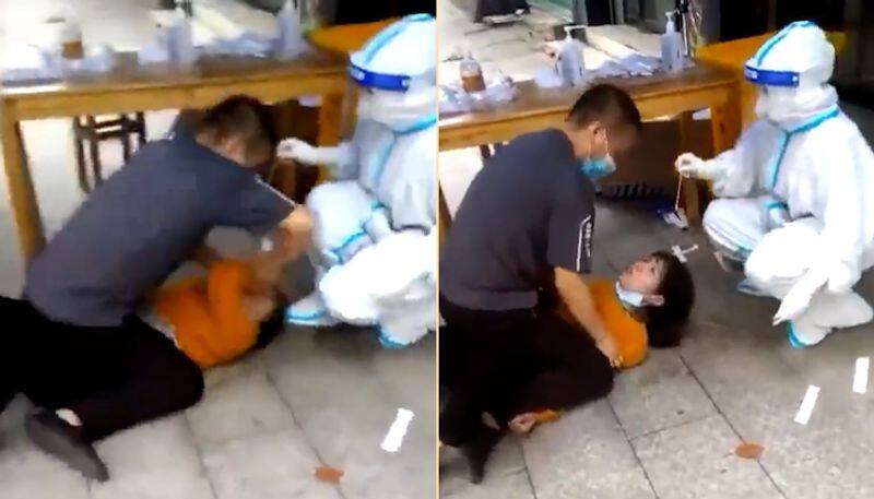 Watch Chinese woman pinned down on floor for forced Covid-19 test-tgy