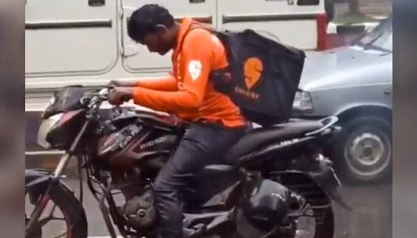 Watch: Swiggy delivery agent waits helplessly in heavy rain at traffic signal; wins netizens' heart