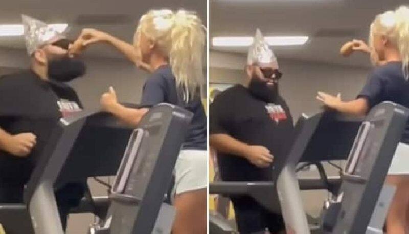 funny video in which woman motivates man to run faster in treadmill by showing him a snack 