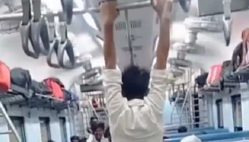 man moving across the train compartment by swinging with the help of the handrest 