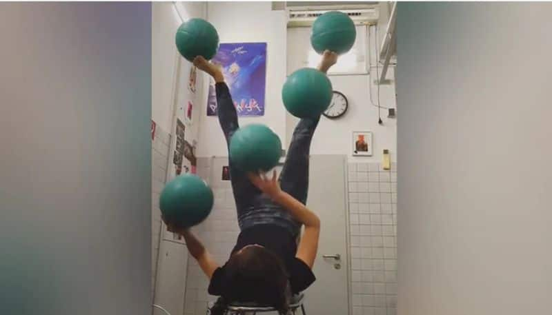 Woman Lying Upside Down On Chair Juggles 5 Balls