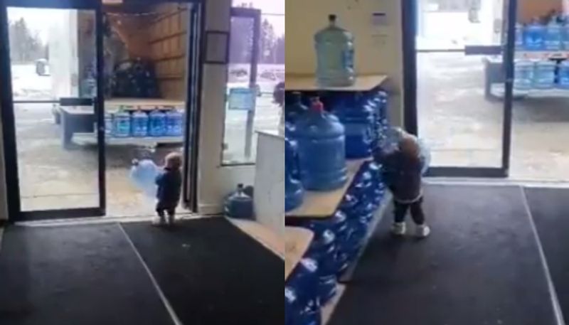 toddler helps mother to unload water jars from a truck 