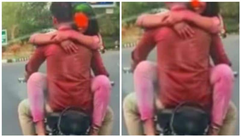 Lady sit on petrol  tank of a RE Bullet and hugged the rider and held by police prn