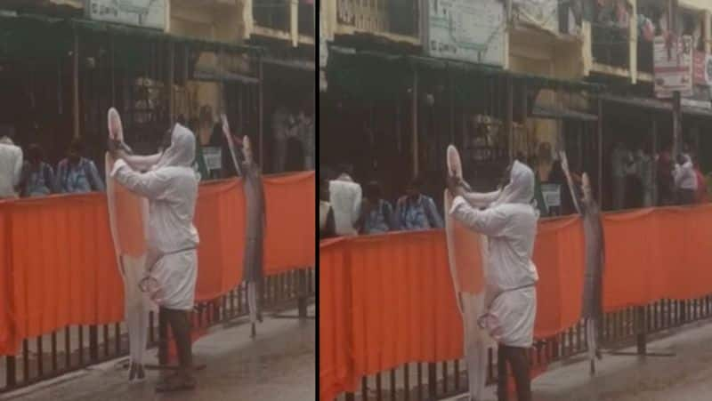 At Devanahalli road show which got rained out, a village man is seen cleaning Modi jis cut out