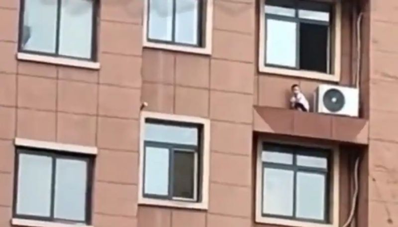 toddler playing on a window ledge of high rise building hyp