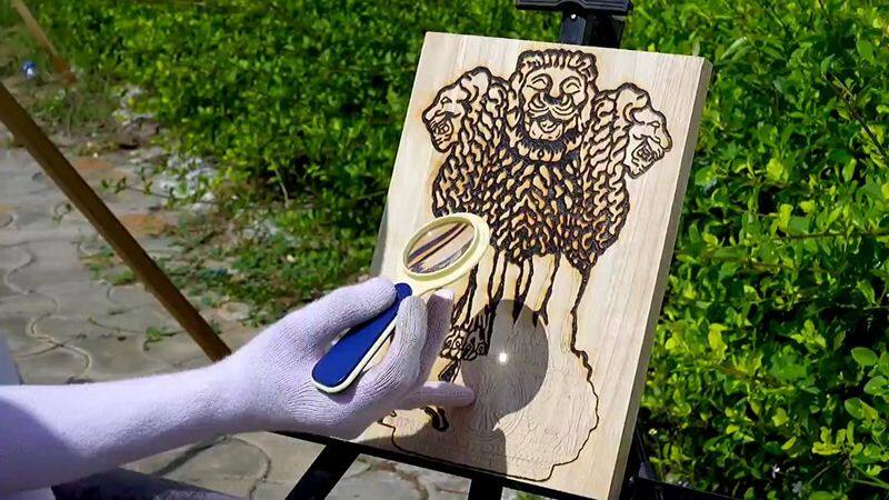 young man draw a ashok chakra for using sun light burning wood art type in thanjavur vel