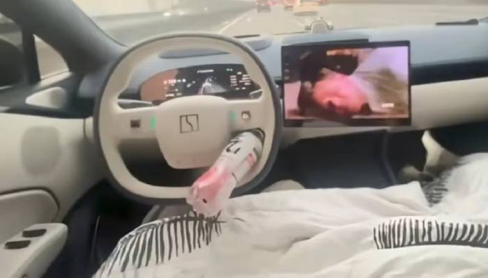 driver using self driving system and sleeping and watching movie in china 