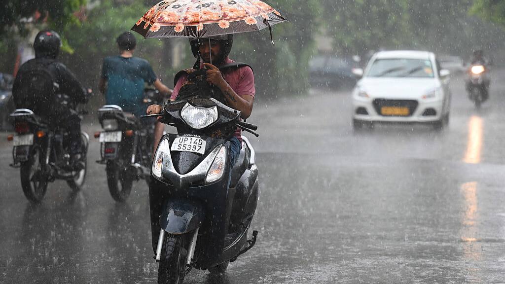 A commuter riding through rain in Delhi