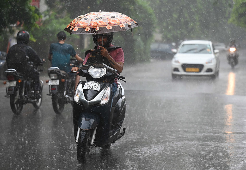 A commuter riding through rain in Delhi